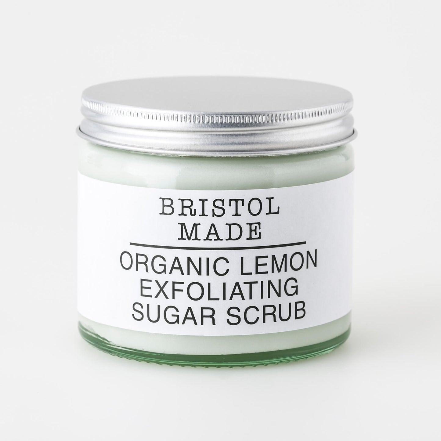 image of a Bristolmade body scrub, highlighting its rich ingredients and exfoliating particles. Packed in an eco friendly, 250ml clear glass jar, with a clear label detailing its rejuvenating and nourishing properties.