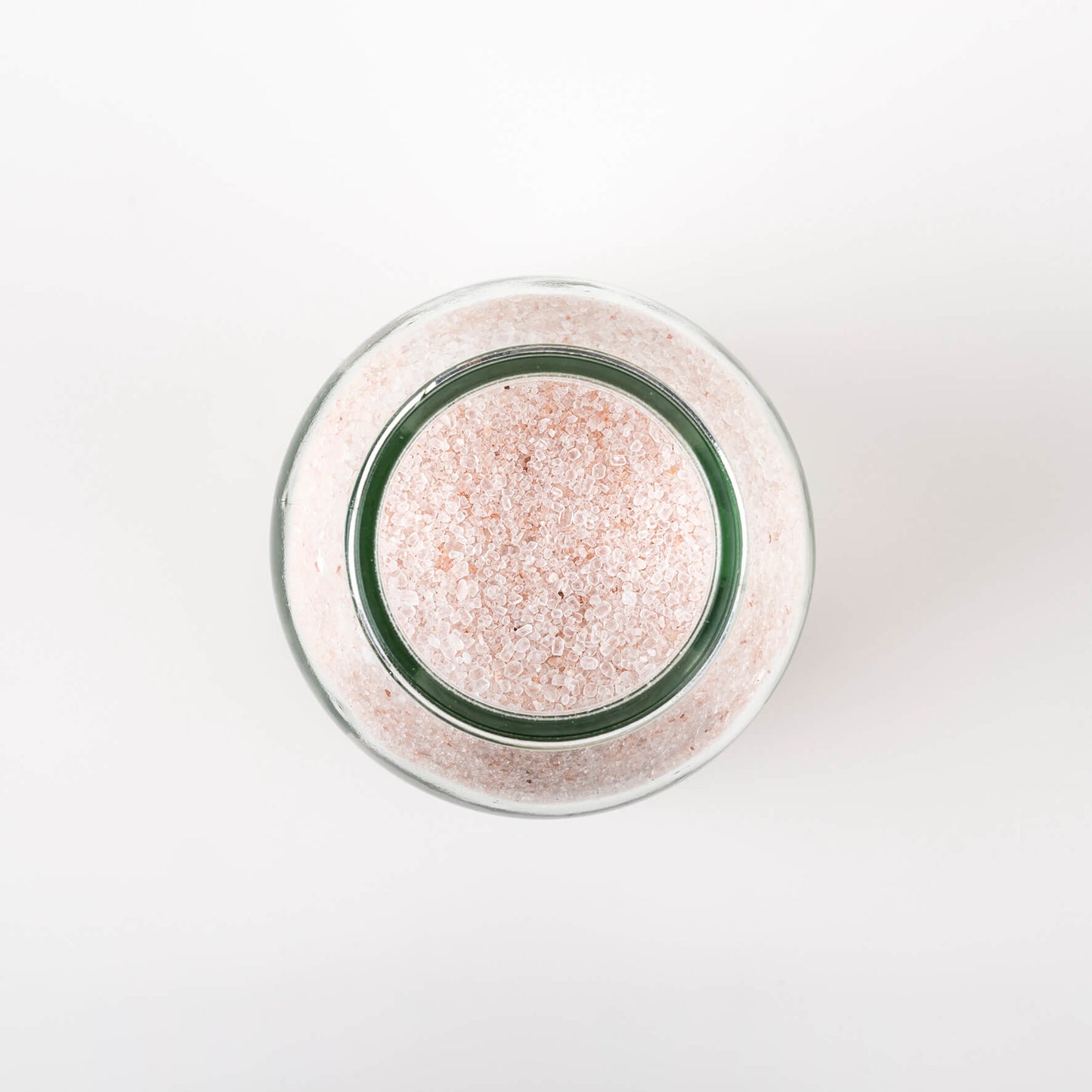 top view of a jar of bath salts, showing the pale pink granules of the epsom salts