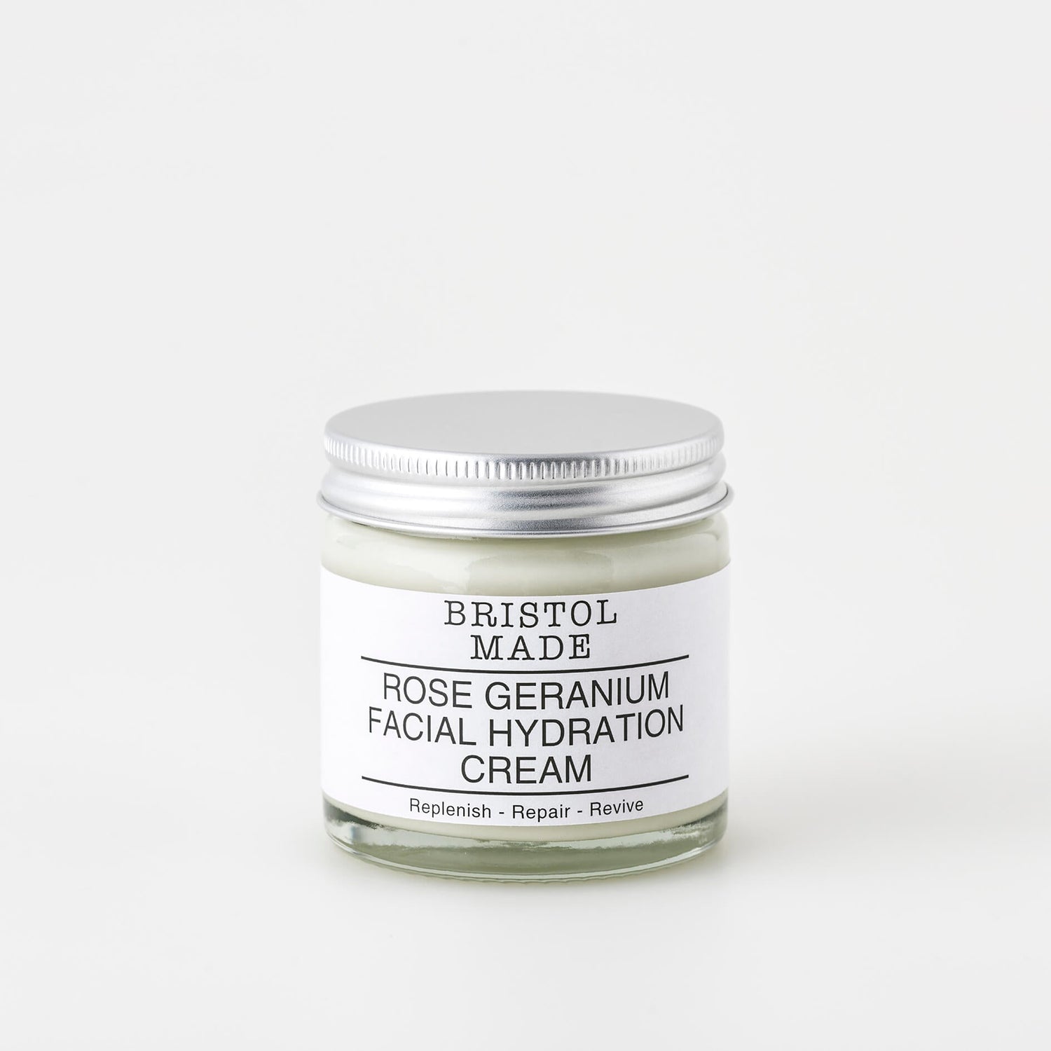 A 60ml clear glass jar of Bristolmade Facial Hydration Cream Rose Geranium, featuring a white label with black text, highlighting its vegan ingredients. 